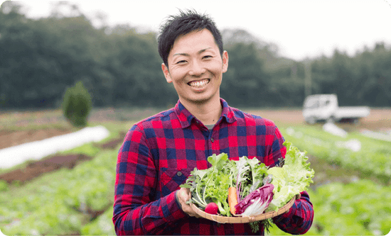 柴海農園さんが笑顔でお野菜を持っている様子